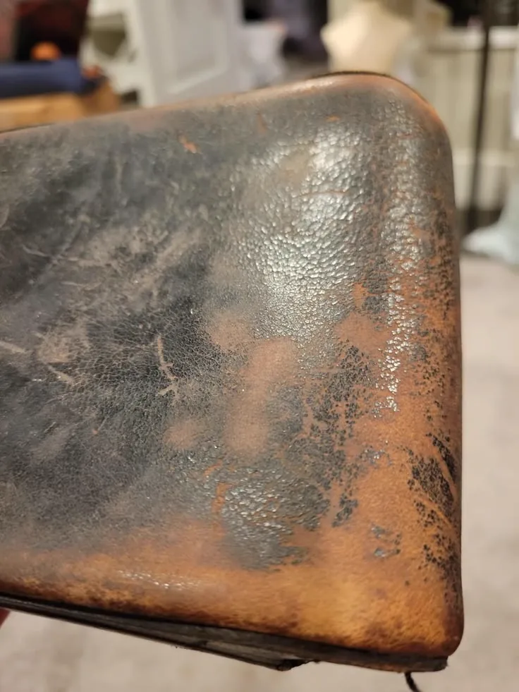 Cracked, worn leather club chair before restoration